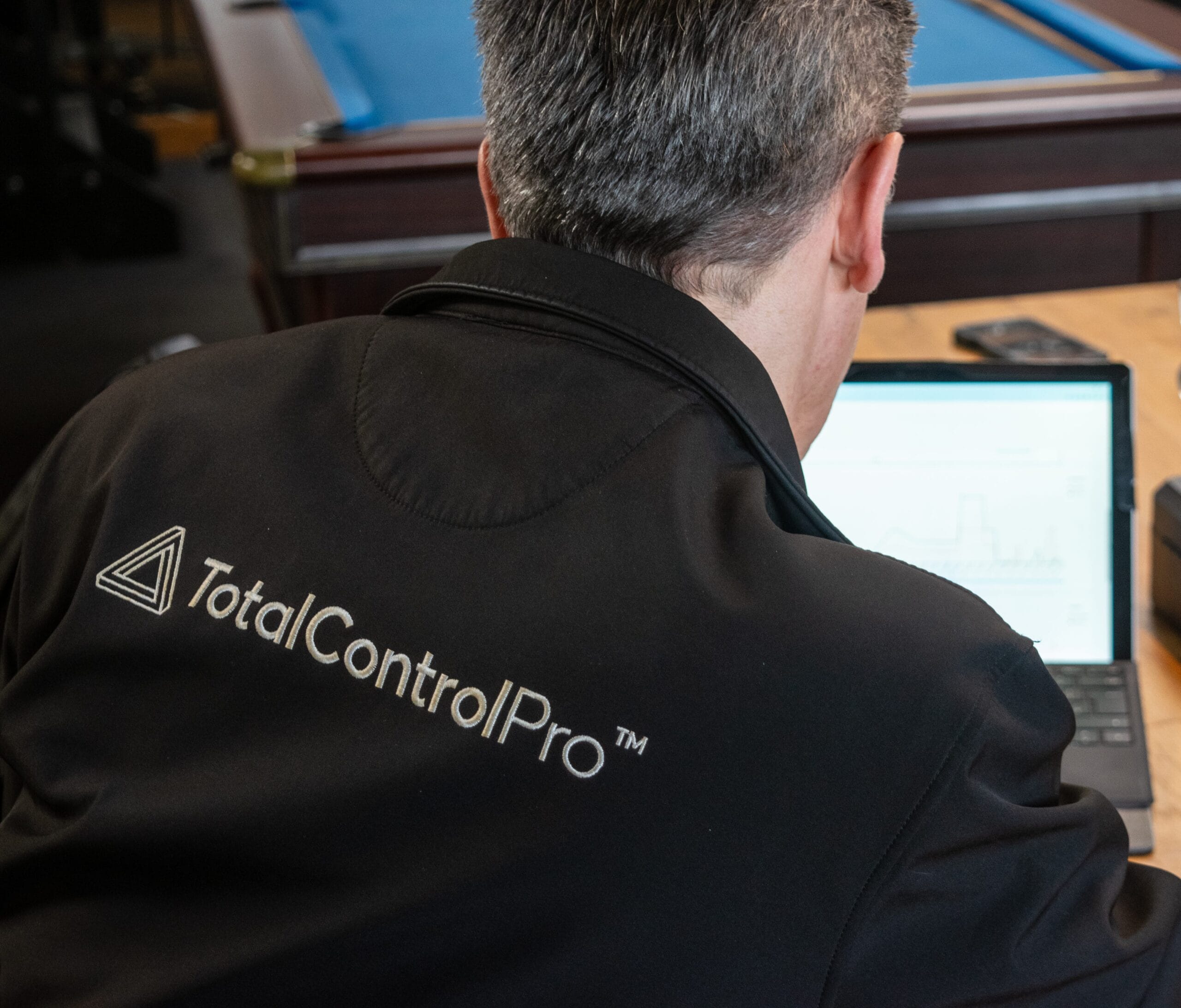 Person with TotalControlPro jacket working on laptop.