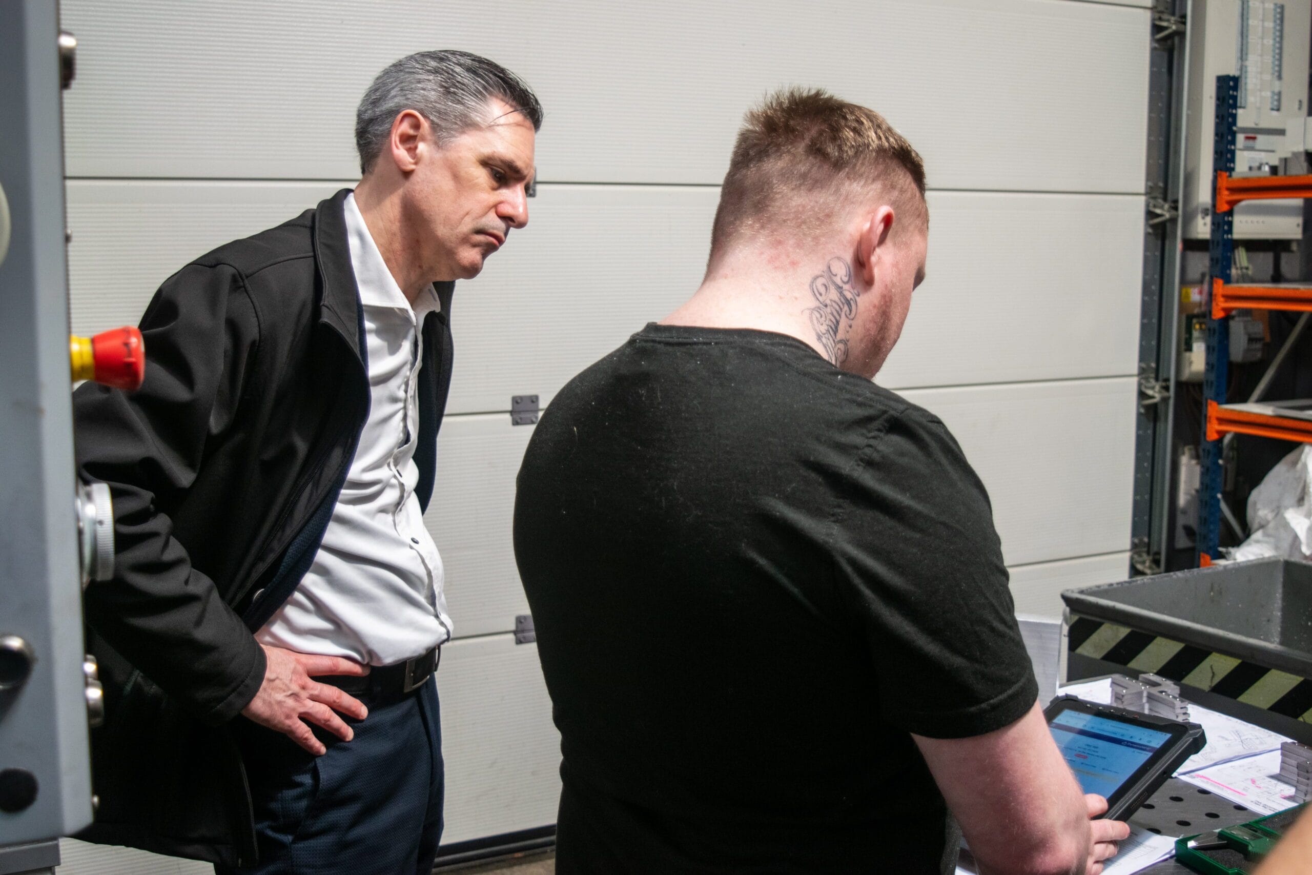 Two men working in industrial setting with tablet.
